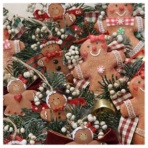 Detail of resin gingerbread man ornaments nestled in pine branches with red ribbons