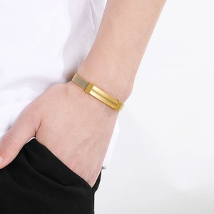 Close-up of golden mesh stainless steel bracelet with a polished metal plate on wrist