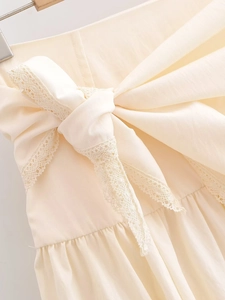 Detail of light beige skirt showing delicate lace trim and ribbon bow decoration