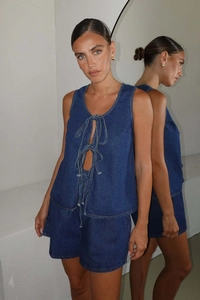 Detail of dark blue denim two-piece set featuring a lace-up vest and matching shorts