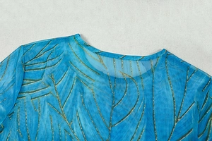 Detail view of blue mesh dress with gold-green leaf print and crew neckline design