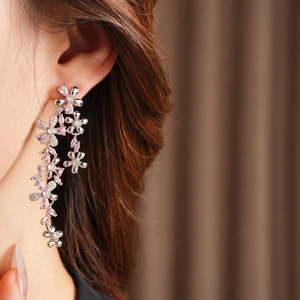 Close-up of sparkling flower tassel earrings with pink and white cubic zirconia on a model