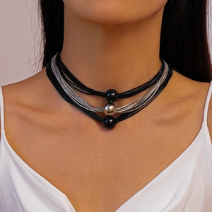 Detail of layered necklace featuring black woven cord, silver chains and round bead charms