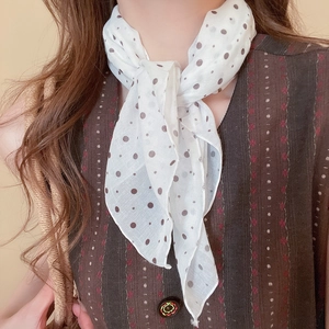 Close-up of a white and brown polka dot neck scarf tied in an elegant French style