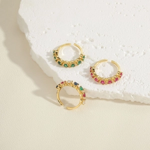 Three minimalist gold open rings with colorful zircon stones on a white stone base