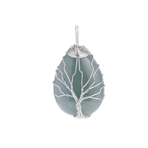 Detail of tree of life pendant with green crystal and silver wire wrapping craft