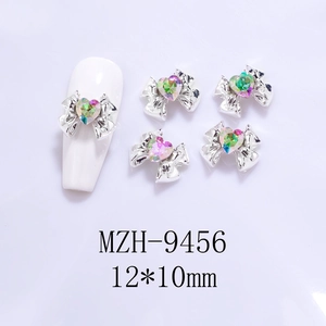 Close-up of 12x10mm alloy bow nail charms with colorful heart crystals on white nails