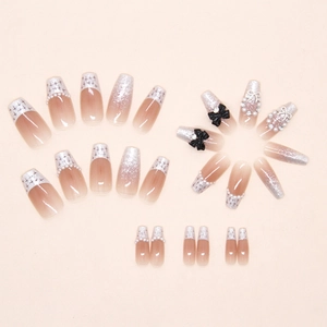 Dettaglio di unghie finte con fiocchi 3D neri, perle e glitter argento french tip
