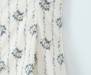 Detail of soft off-white chiffon fabric with blue daisy floral pattern and smooth texture