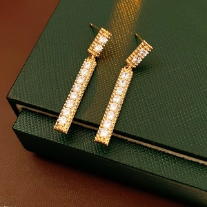 Détail de boucles d'oreilles pendantes dorées avec zircons sur boîte verte