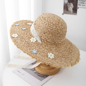 Close-up of floral embroidery and lace ribbon on a frayed edge straw sun hat