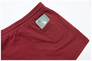 Detail of burgundy ribbed shorts with elastic waist and back pocket holding a smartphone