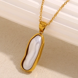 Vue macro d'une chaîne plaquée or 18K avec pendentif perle baroque sur décor minimal