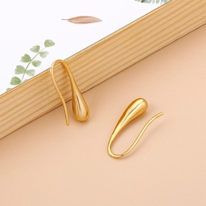 Close-up of golden teardrop earrings on minimalist background with natural decor
