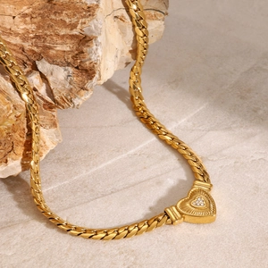 Macro detail of gold-plated heart pendant with rhinestones on a thick cuban chain