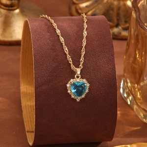 Halskette mit blauem Kristallherz und goldener Wellenkette auf edlem Schmuckständer