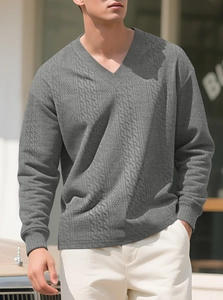 Detail of grey V-neck knit sweater showing intricate jacquard texture and relaxed fit
