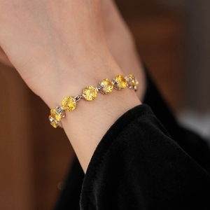 Close-up of a sparkling yellow zircon round-cut tennis bracelet on a model wrist
