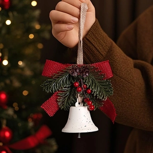 Detail of Christmas bell ornament with red linen bow, green pine needles and berries