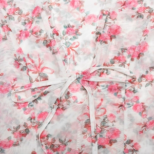 Détail macro de la robe en tulle blanc avec imprimé roses roses et nœud papillon à cordon