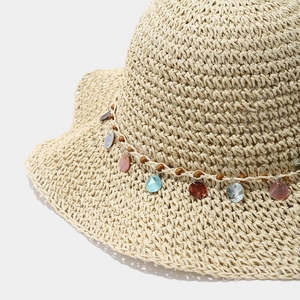 Détail du chapeau de paille avec pendentifs en coquillages colorés et perles en bois