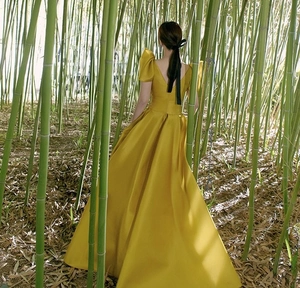 Detail of elegant yellow satin dress with puff sleeves and deep V-back in bamboo forest