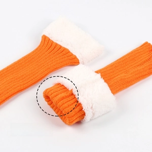 Close-up of bright orange ribbed knit leg warmers with thick white faux fur lining
