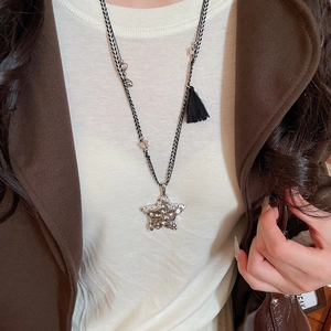 Détail d'un pendentif étoile en argent sur un collier tressé porté par un mannequin