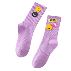 Purple crew socks with yellow smiley face patches and letter embroidery on white background
