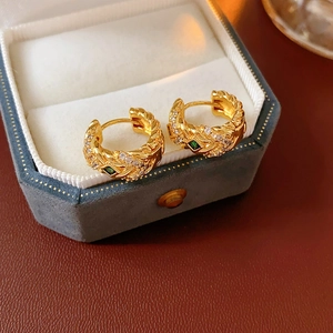 Detail view of gold zircon earrings with green gemstones in a velvet jewelry box