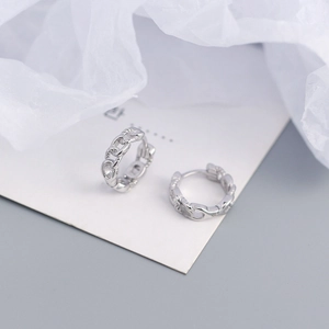 Macro detail of S925 sterling silver chain link huggie hoop earrings on white silk