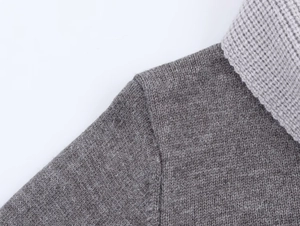 Close-up of the grey knit top fabric texture and color block contrast on the shoulder
