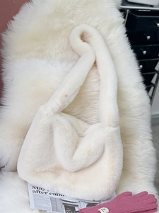 Detailed close-up of fluffy cream faux fur shoulder bag texture with soft plush fabric