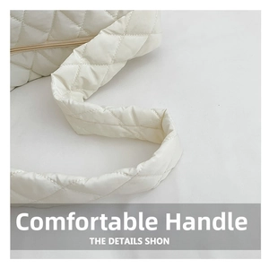 Detail of white quilted tote bag featuring wide padded handles and soft puffy texture