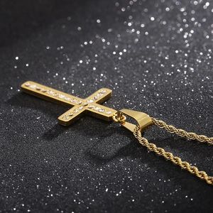 Macro shot of gold cross pendant with cubic zirconia stones on twisted rope chain