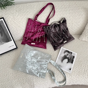 Detail of velvet tote bags with pearl bead fringe and vertical stitching accents