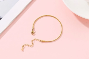 Close-up of golden snake chain bracelet with adjustable lobster clasp and extender