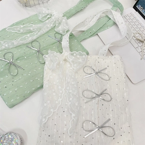 Close-up of sequined canvas tote with lace trim and silver bow details in mint and white