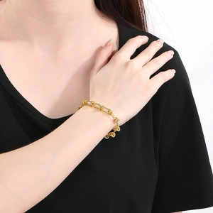 Gros plan d'un bracelet gourmette doré à nœud porté au poignet, style minimaliste