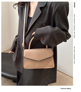 Fashionable khaki square handbag with rivet trim and top handle in a lifestyle setting