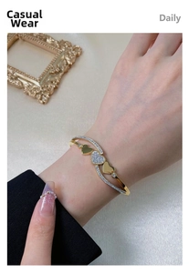 Detail of a gold stainless steel bangle with rhinestone hearts on a female wrist