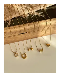 Detail showing five gold snake chain necklaces with diverse geometric pendant designs