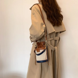 Retro canvas and brown leather bucket bag with contrast trim on a model in trench coat