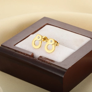 Detail view of gold handcuff stud earring with sparkling crystal on a jewelry box