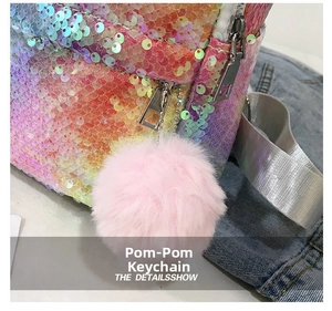Detail showing a fluffy pink pom pom charm on a colorful sequin backpack zipper