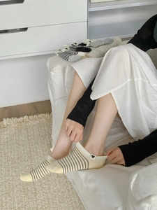 Detail of yellow striped cotton low cut socks with heart embroidery on model's feet