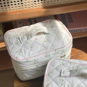 Detail of quilted floral cosmetic bags with bow patterns and durable top handles