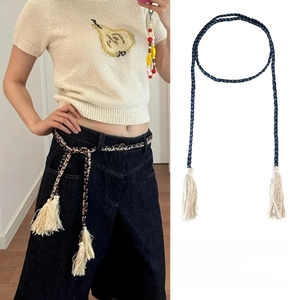 Detail of woven fringe belt showing tassel ends in dark coffee and blue-black colors
