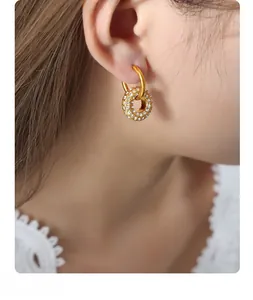 Detail of gold geometric hoop earrings with sparkling rhinestones worn by a model