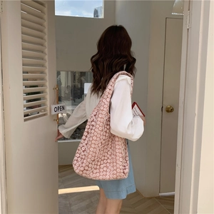 Pink floral lace canvas tote bag carried by a model standing near an open white door
